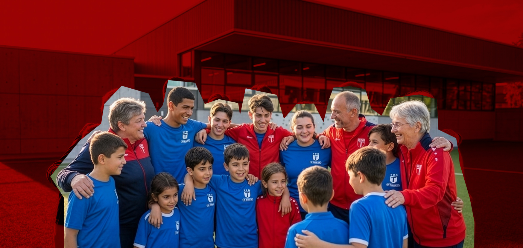 Eine Gruppe von Fußballspielern und Trainern in blauen und roten Trikots posiert lächelnd auf einem Sportplatz.